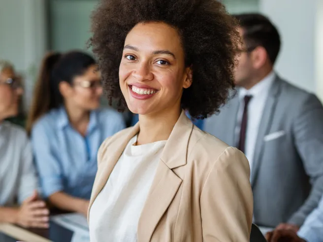 Lächelnde Frau mit Tablet im Verwaltungsbüro, im Hintergrund das Backoffice von PFLEGEN & WOHNEN HAMBURG.