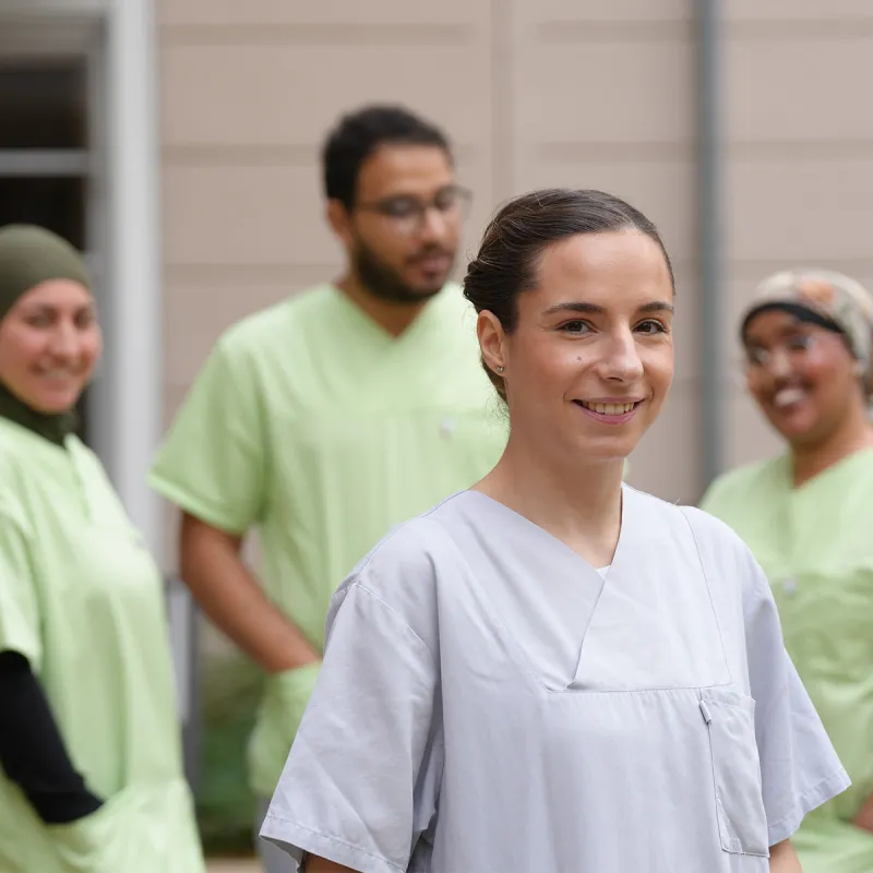 Auszubildende Pflegefachkraft bei PFLEGEN & WOHNEN HAMBURG mit unterstützenden Kollegen.
