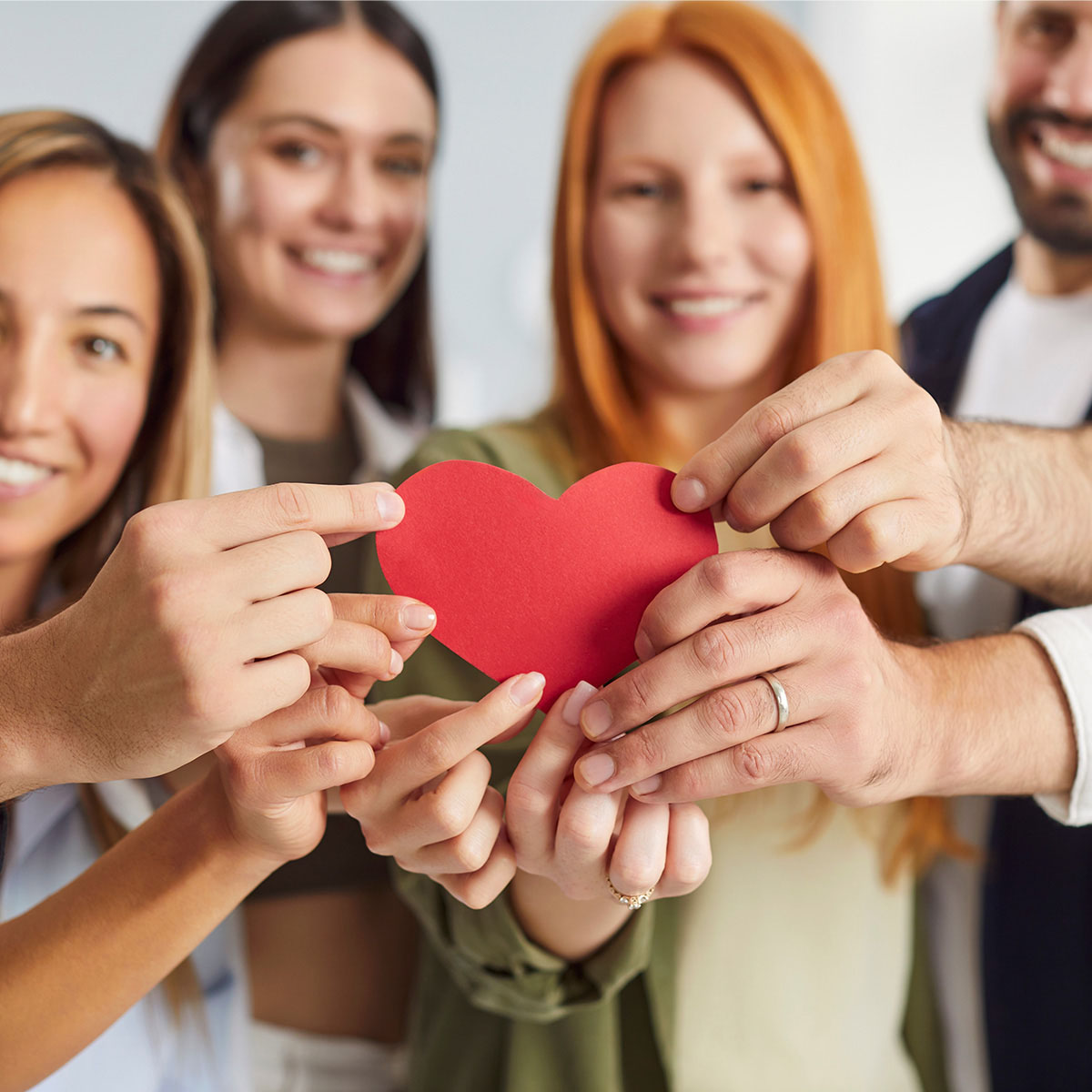 Mitarbeiter von PFLEGEN & WOHNEN HAMBURG halten ein rotes Herz als Symbol für die gemeinsame Philosophie.